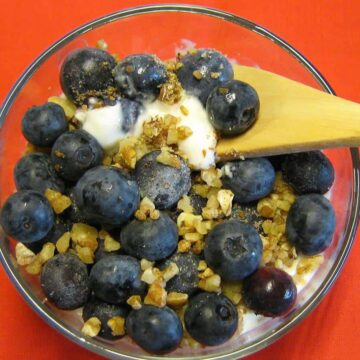 Blueberries and granola in cup with wooden spoon