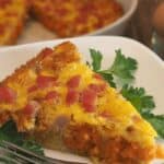sweet potato tot and ham casserole wedge on white plate with parsley garnish