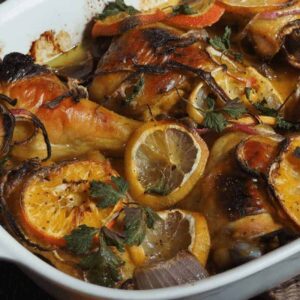 honey roasted chicken in pan with sliced oranges