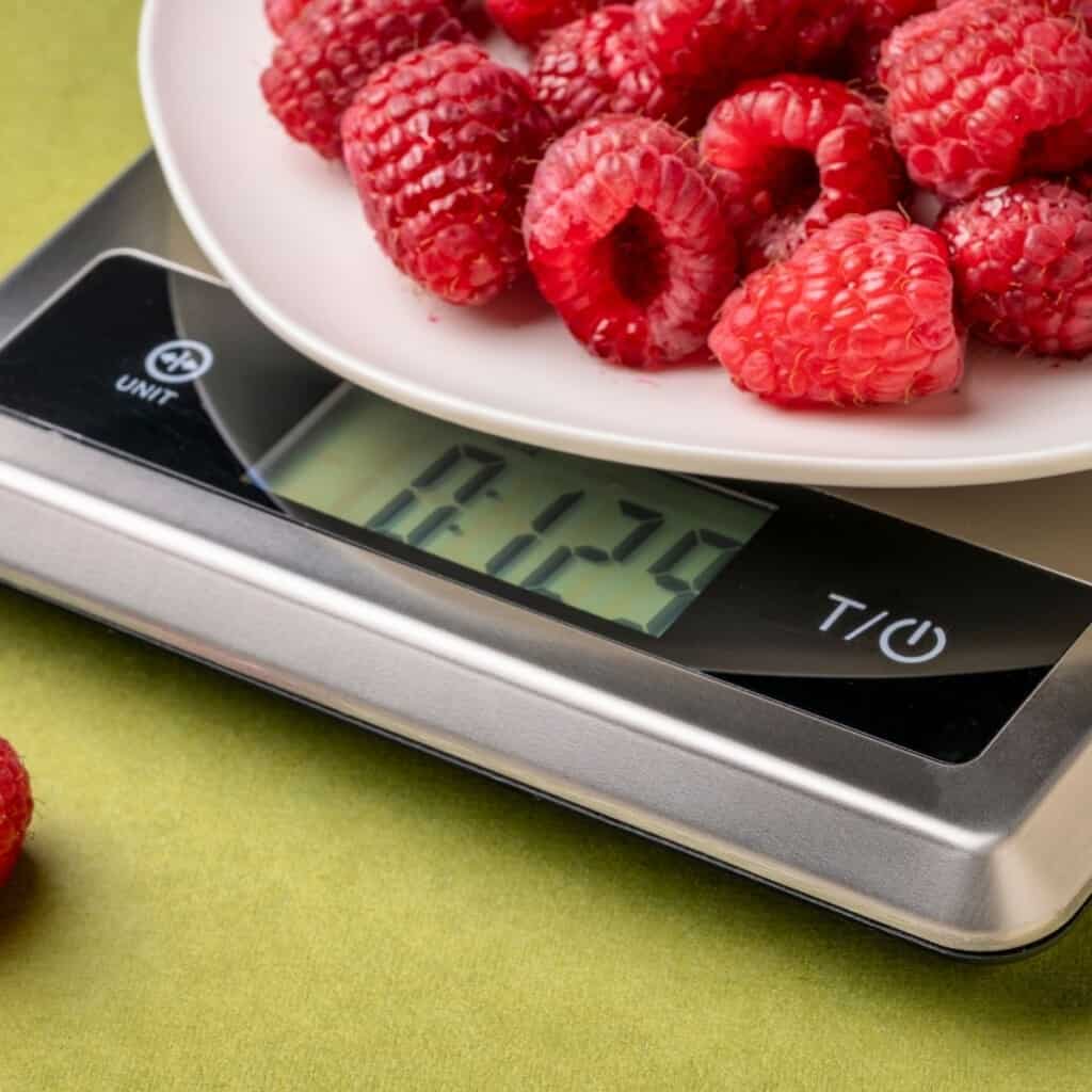scale with raspberries on yellow counter