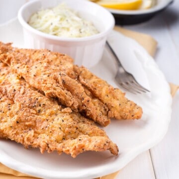 2 fried catfish filets with small bowl of slaw on white plate