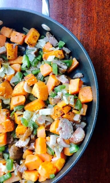 sweet potato chunks with cooked pork, peppers, and onions in skillet