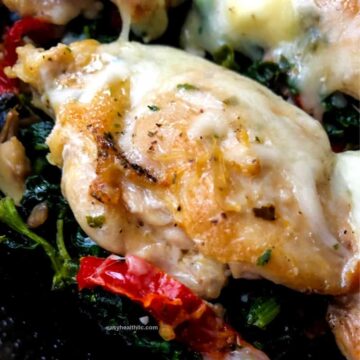 Greek chicken thigh with melted cheese on bed of spinach