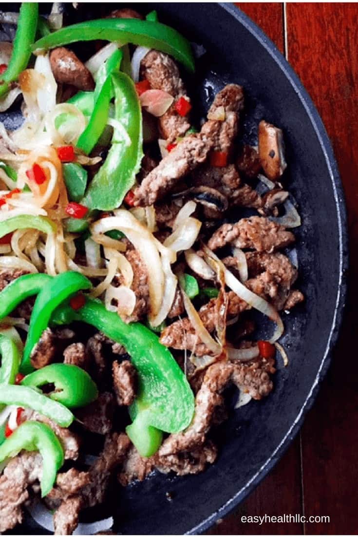 sautéed beef strips, sliced onions and bell peppers in black skillet