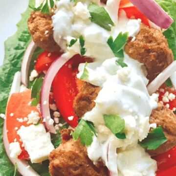 gyro meatballs on lettuce leaf with red onion and tzatziki sauce