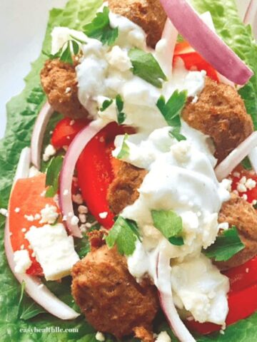 gyro meatballs on lettuce leaf with red onion and tzatziki sauce
