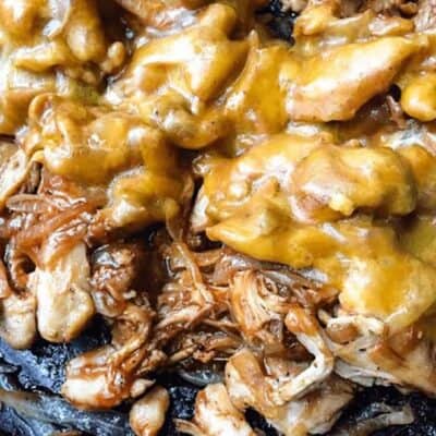 shredded bbq chicken and onions in skillet with melted yellow cheese