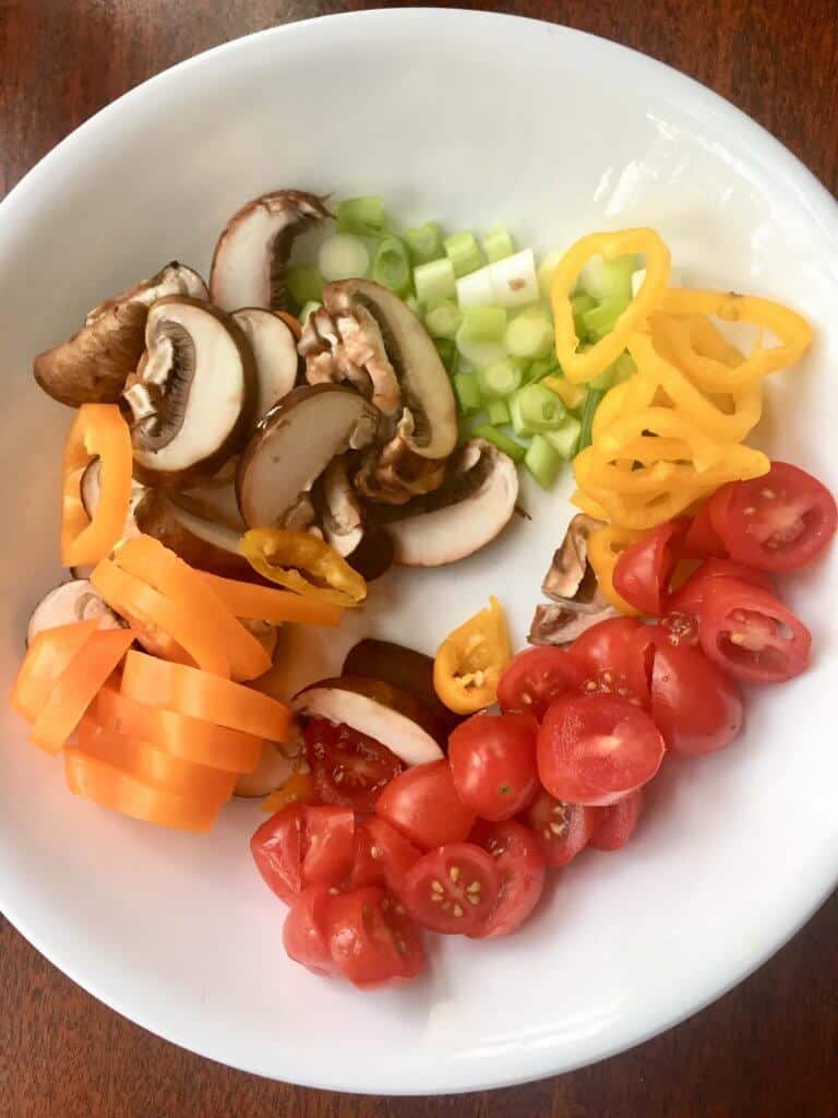white bowl with yellow peppers, cherry tomatoes green onions and mushrooms