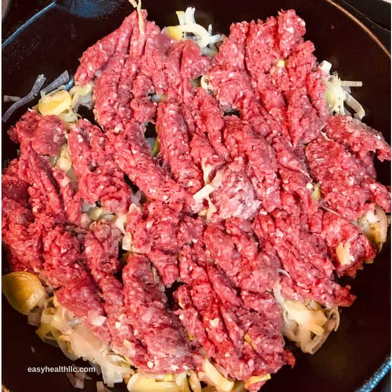 raw ground beef and onions in skillet