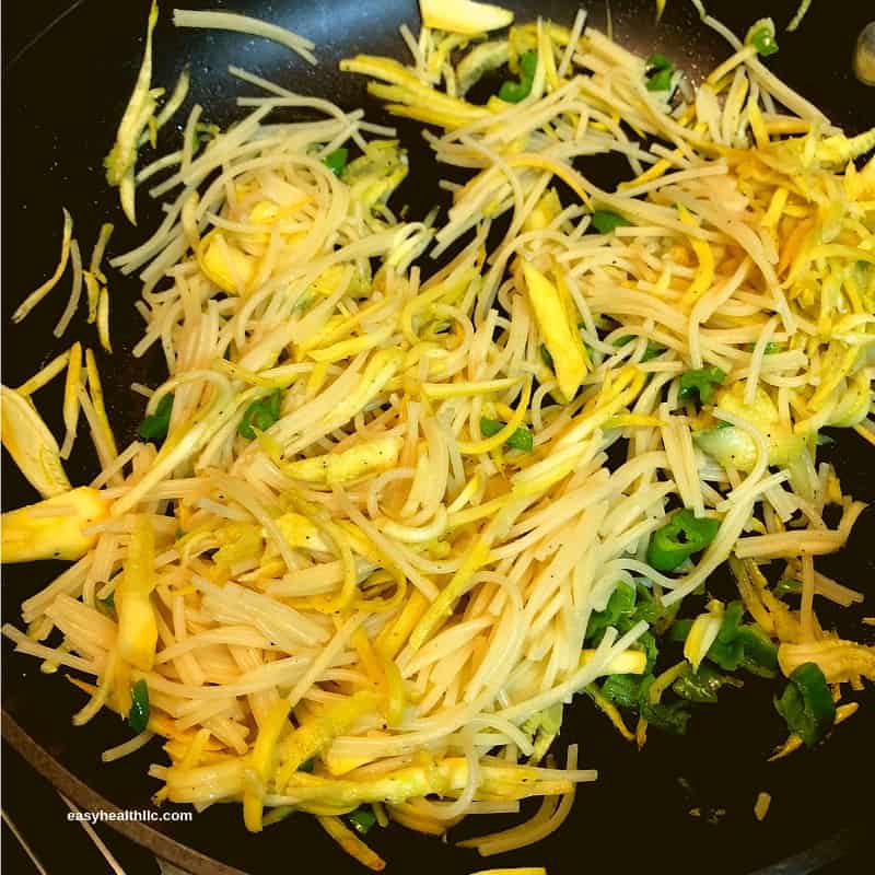 spiralized squash mixed with spaghetti in skillet
