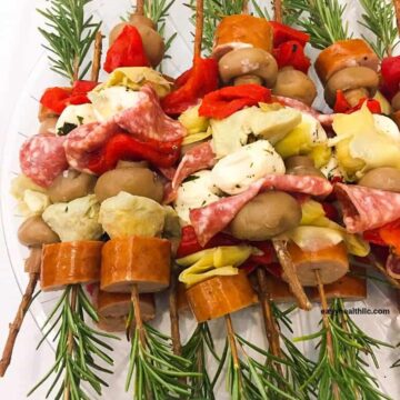 rosemary skewers with sliced sausage,cheese,artichoke on plate