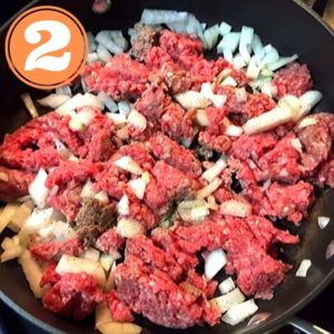 raw ground beef and onions in skillet