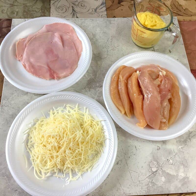 bowls of cheese, raw chicken tenders, ham and measuring cup of hollandaise sauce
