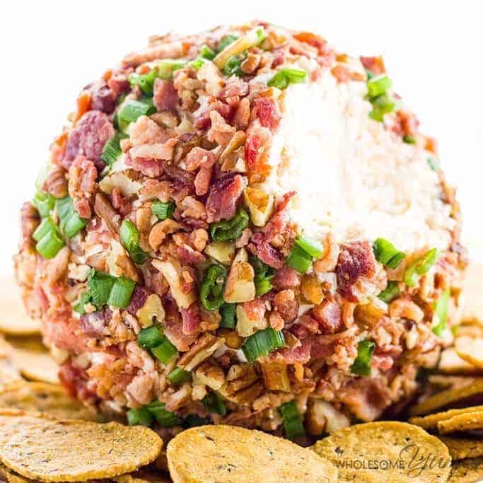 cheese ball coated in chopped pecans and green onions surrounded by round wheat crackers