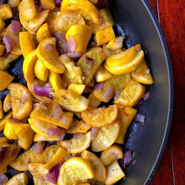 sliced yellow squash and onions in black skillet