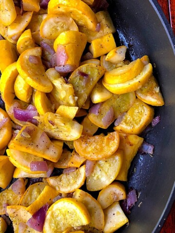 sliced yellow squash and onions in black skillet