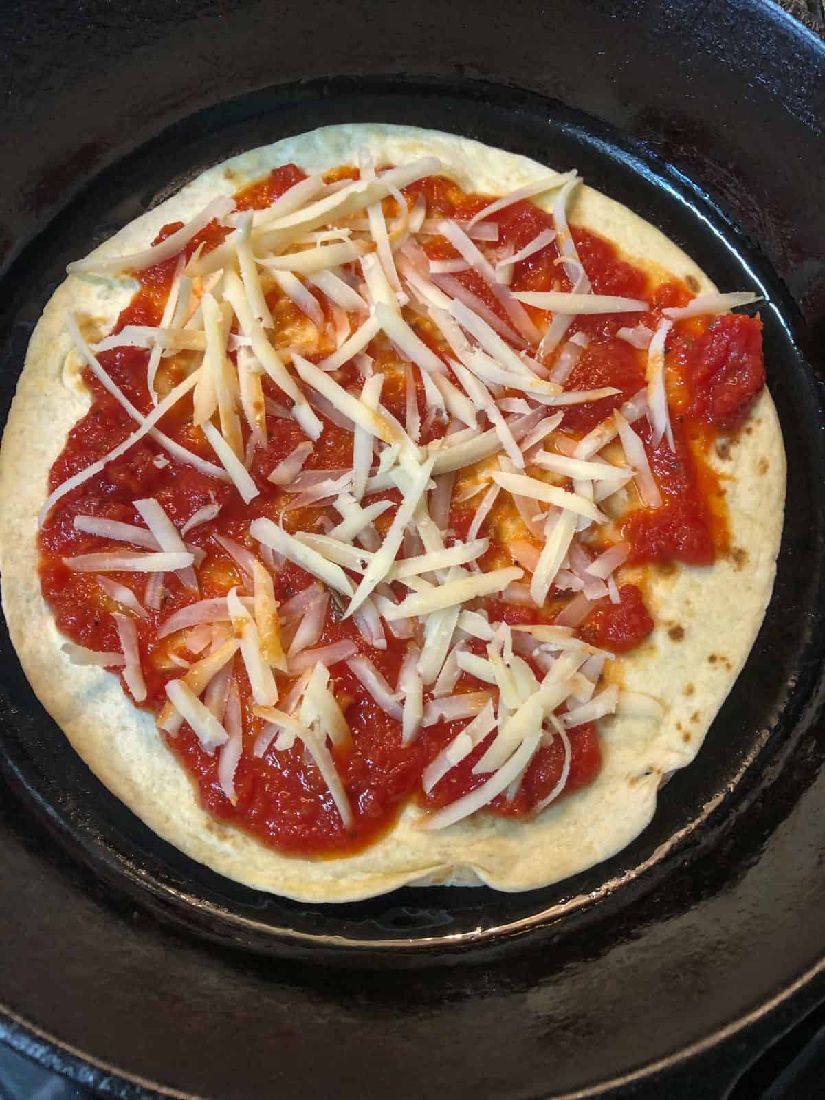 marinara and cheese on tortilla in skillet