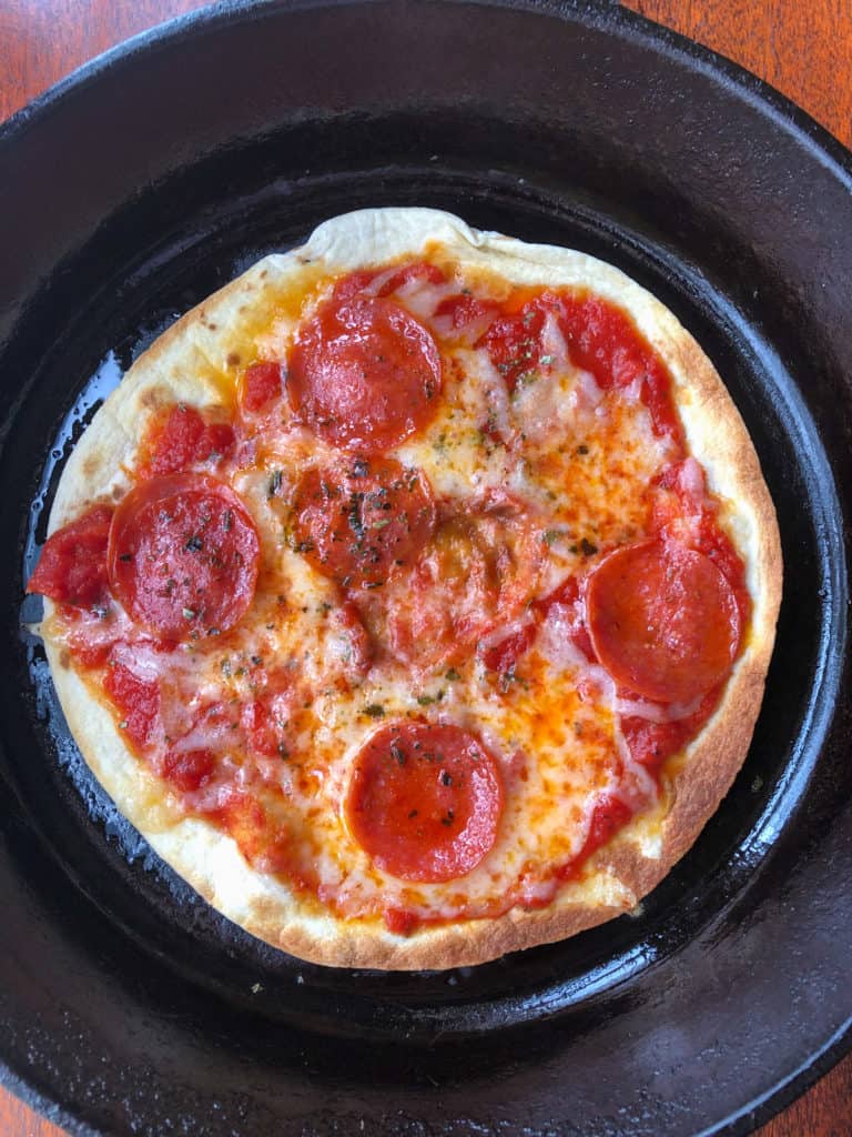 A pizza sitting on top of a pan on a stove, with Cheese and Pepperoni
