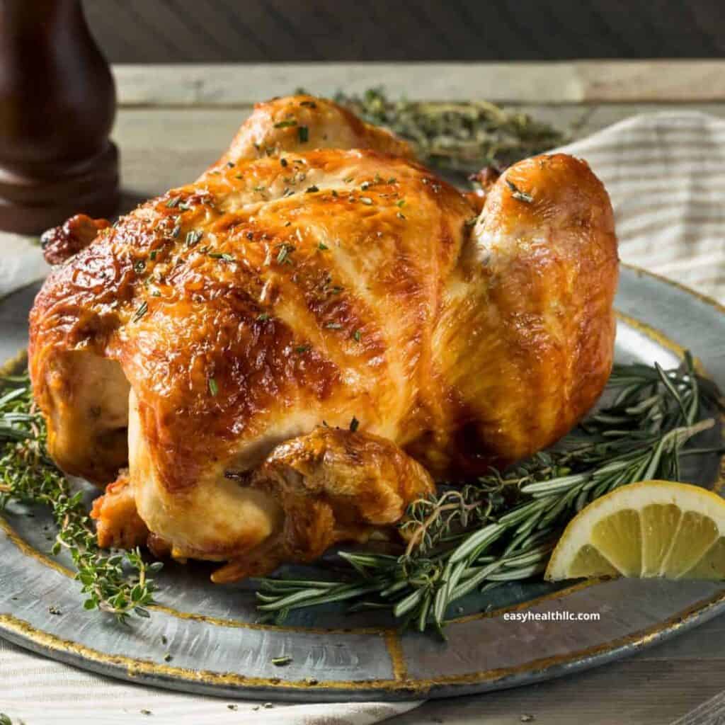 rotisserie chicken on a platter with lemon and herbs