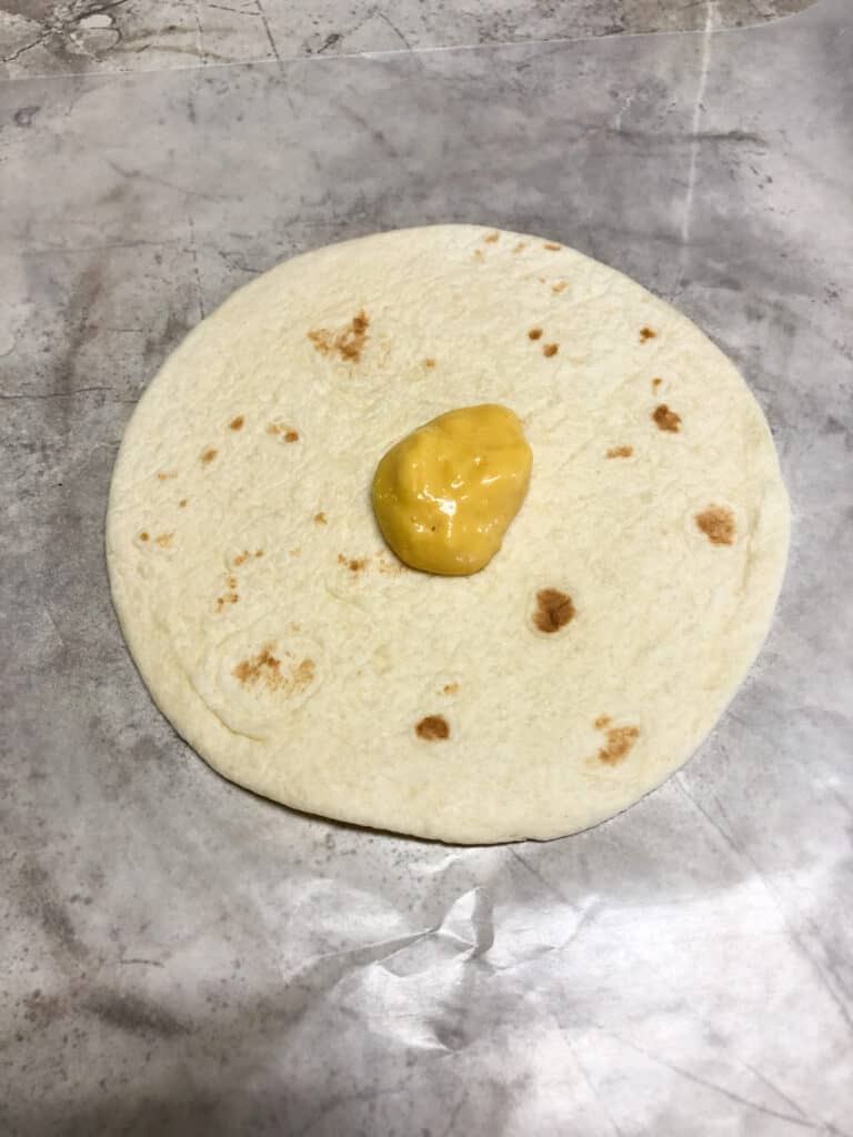 tortilla on cutting board with spoonful of mustard