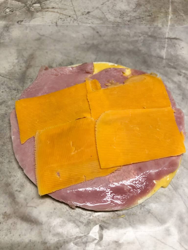 tortilla with ham and cheese on cutting board