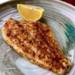 baked fish on plate with lemon