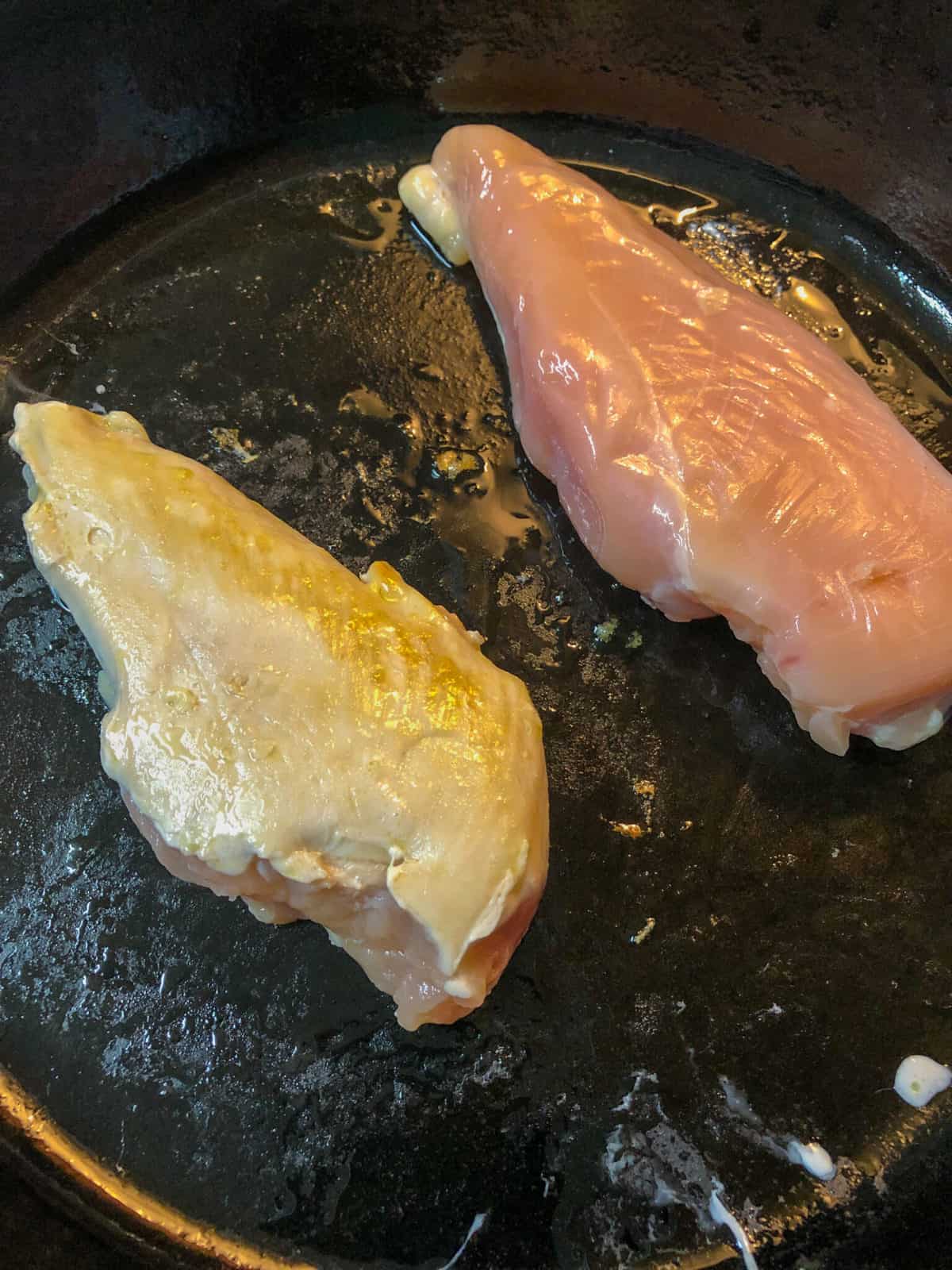 chicken breast sautéing in skillet