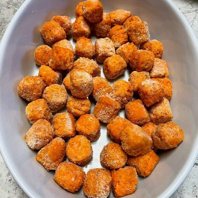 sweet potato tots in bottom of white casserole dish
