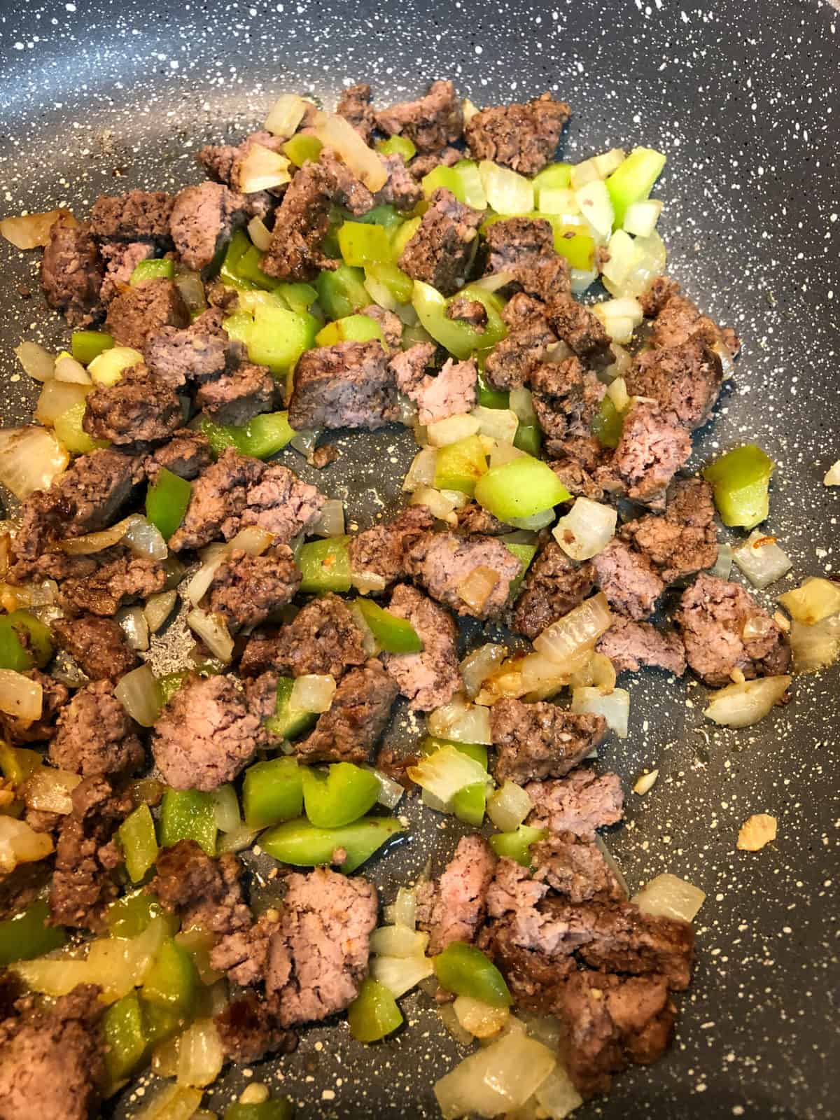 Sautéed meat, peppers and onions in skillet