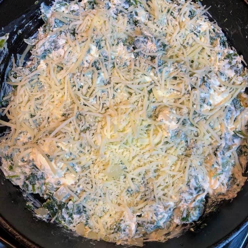 spinach dip topped with grated parmesan in iron skillet