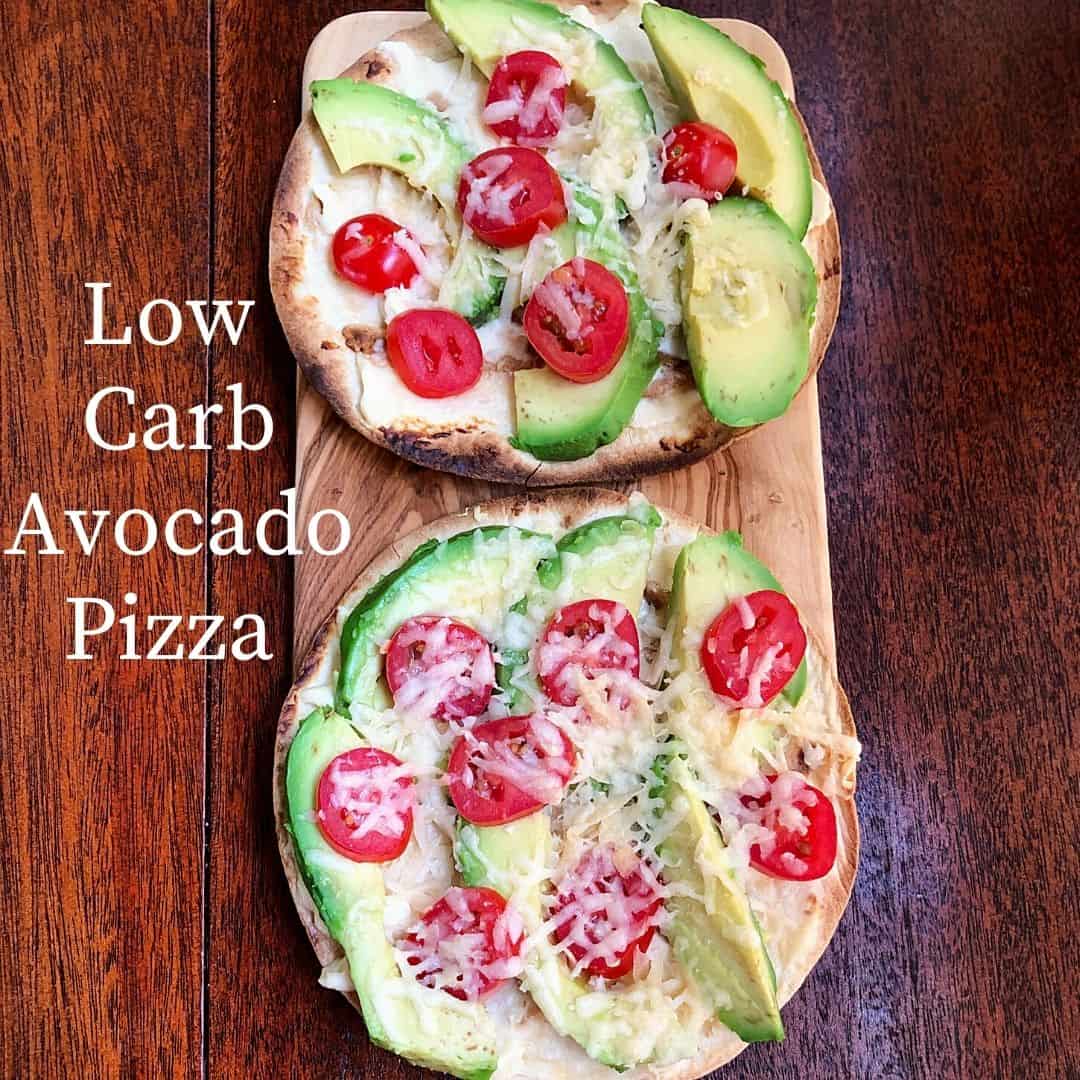 2 avocado pizza with sliced tomatoes on wooden cutting board