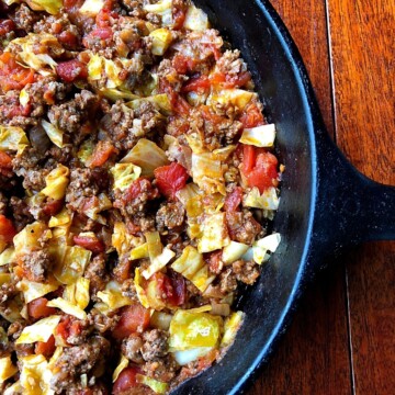 chopped cabbage, ground beef and tomatoes in iron skillet