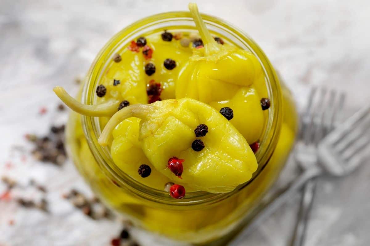 close up of pepperoncini peppers in glass jar