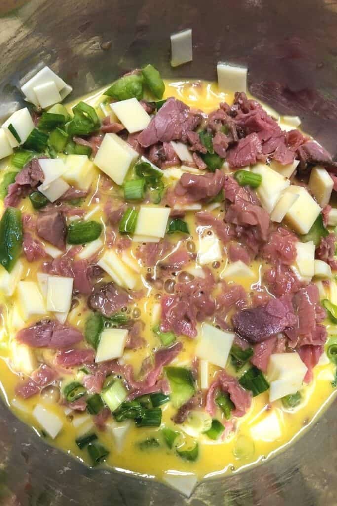 roast beef, cheese,eggs,green peppers in eggs ready to bake