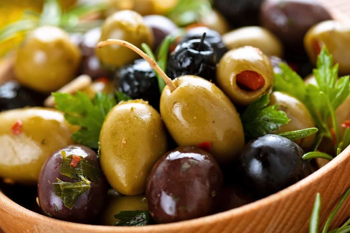 black, green and stuffed olives in brown bowl