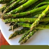 Cooked asparagus spears on white plate.