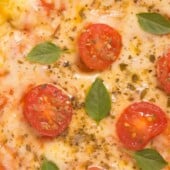 closeup cauliflower pizza with cherry tomatoes and basil leaves