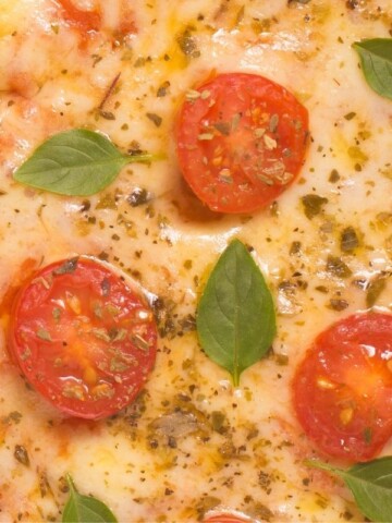 closeup cauliflower pizza with cherry tomatoes and basil leaves