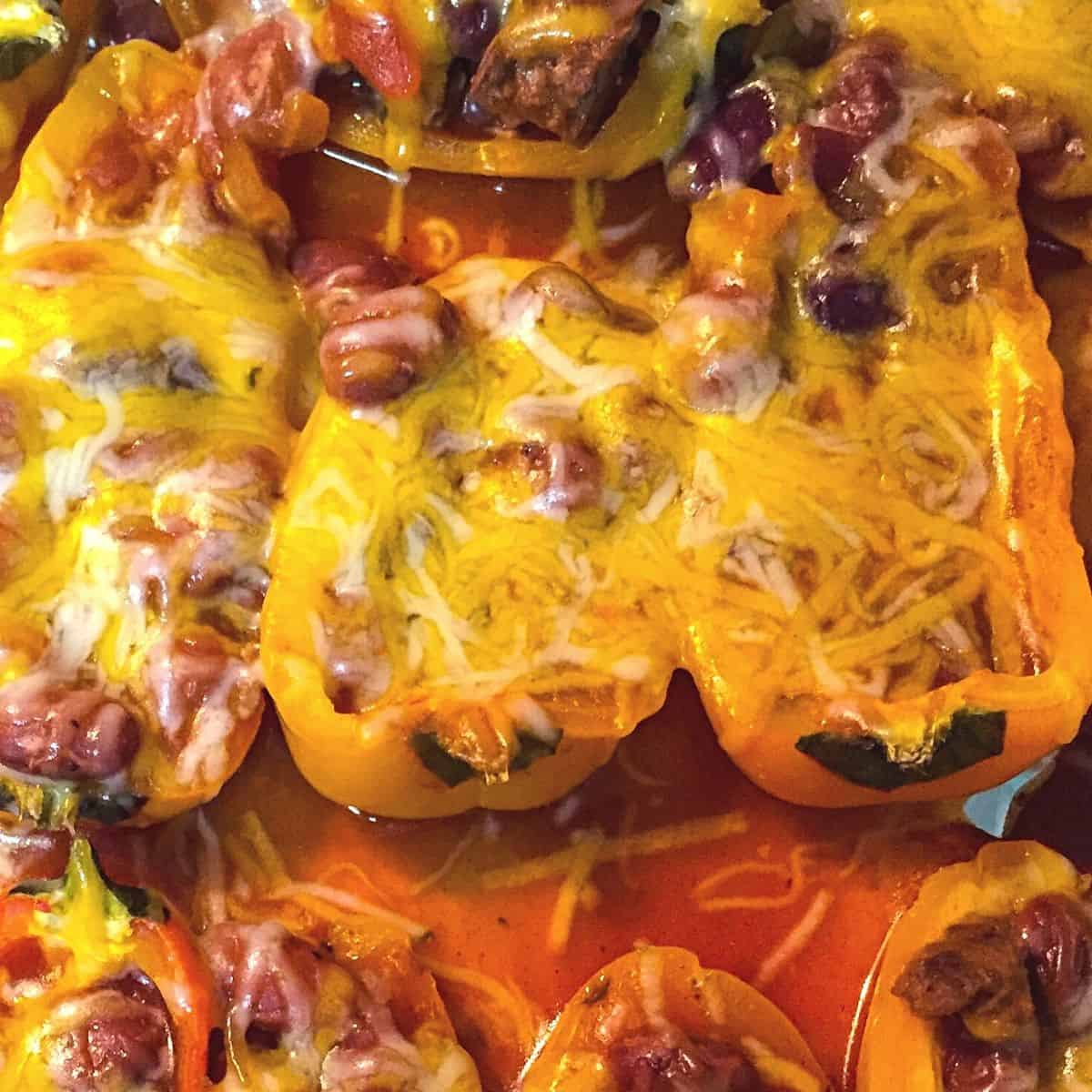 red and yellow mini peppers stuffed with chili and melted cheese on top