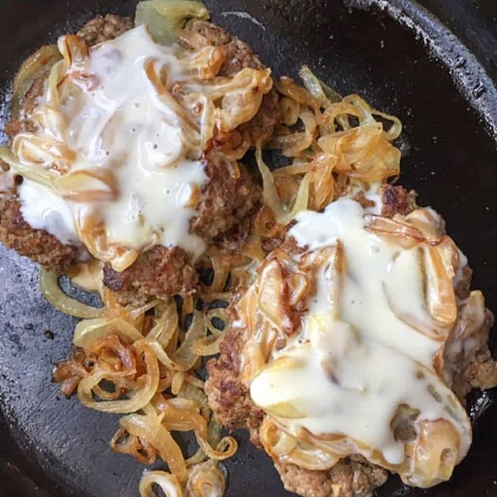 beef patties with melted queso and caramelized onions on top