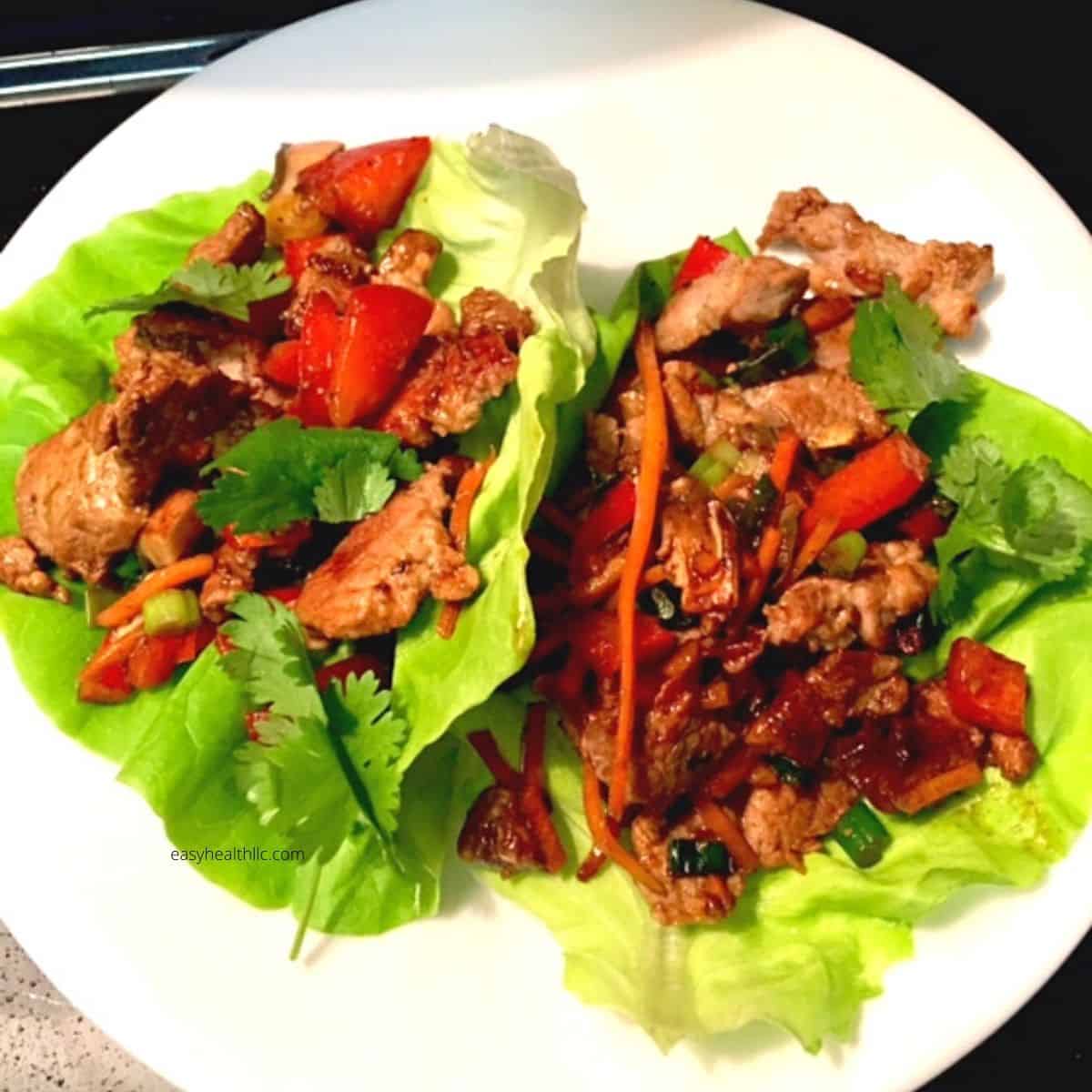 pork, red bell peppers on green lettuce leaves