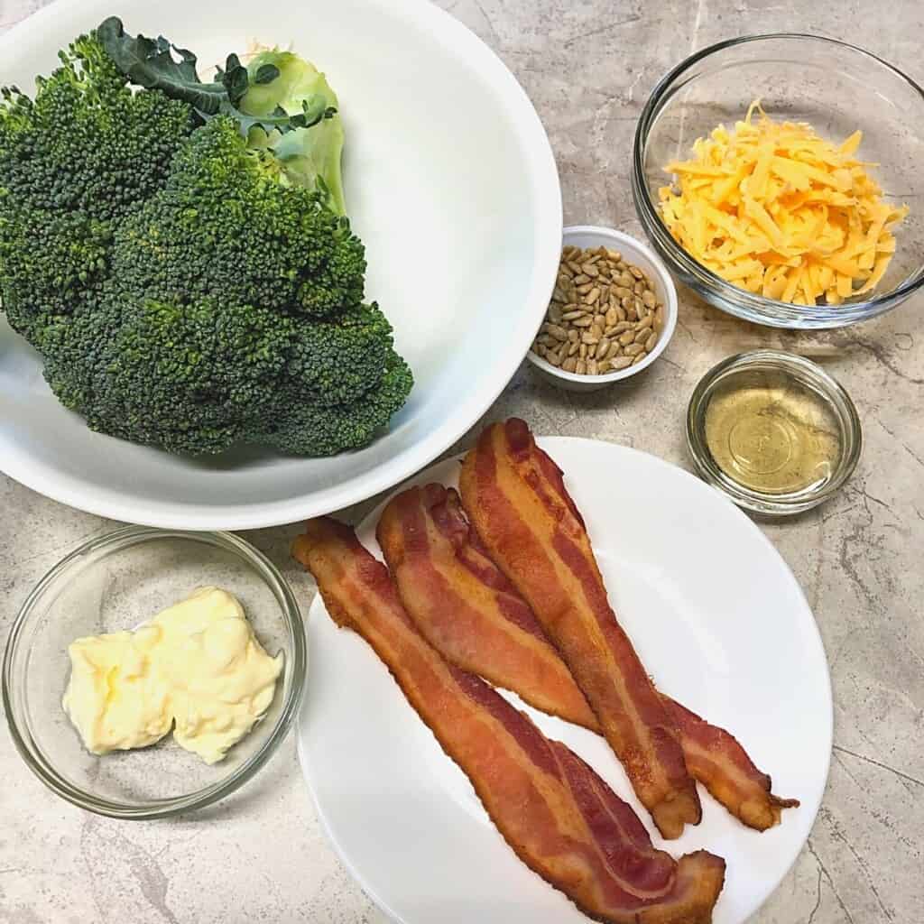 bowl of broccoli, bacon strips, sunflower seeds, grated yellow cheese and mayonnaise