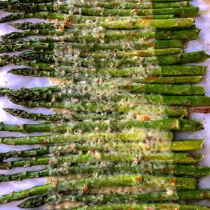 asparagus spears with white cheese melted on top on parchment paper