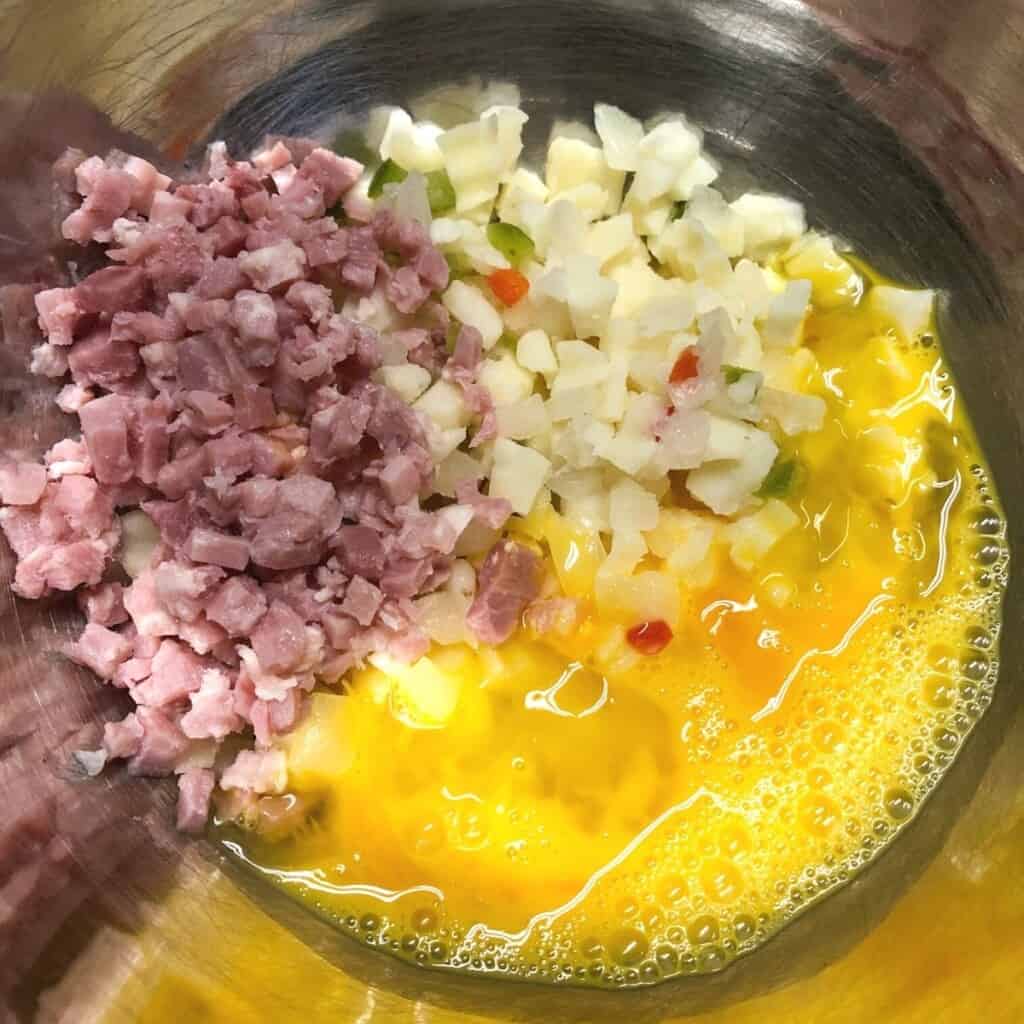 diced ham, hash browns and eggs in a metal mixing bowl