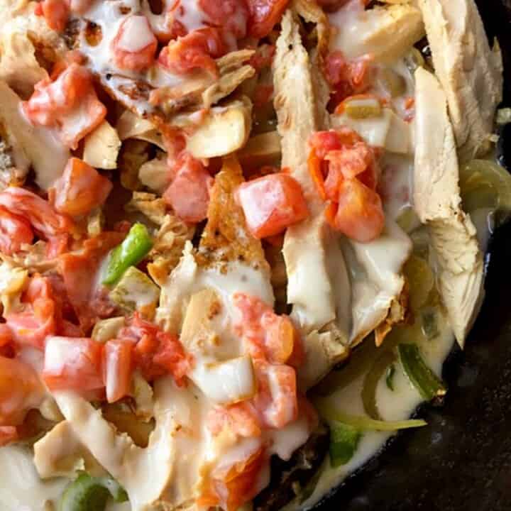 chicken tomatoes peppers and queso in black skillet 