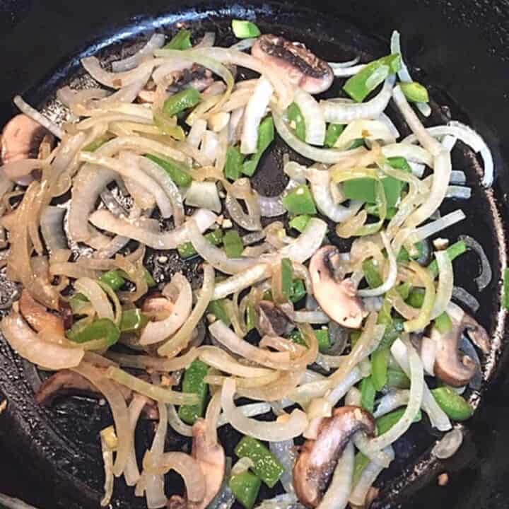 sliced peppers and onions in black skillet