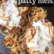 Patty melts with onions and melted cheese in iron skillet.