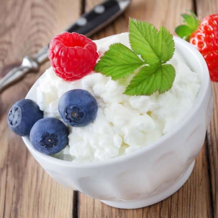 cottage cheese with blueberries on top in white bowl on wooden counter