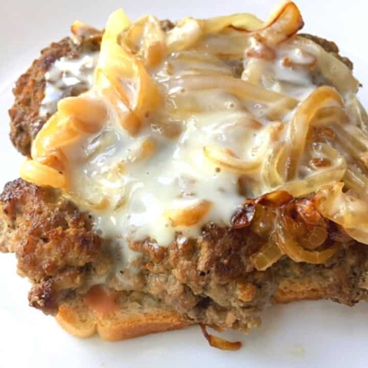 beef patty with queso and onions on top on white plate