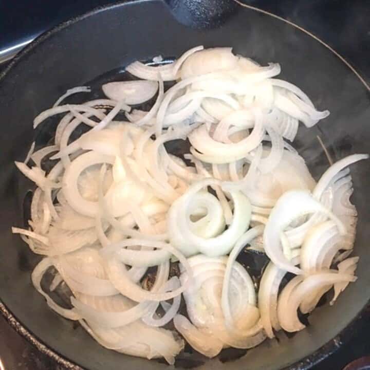 sliced white onions in black skillet